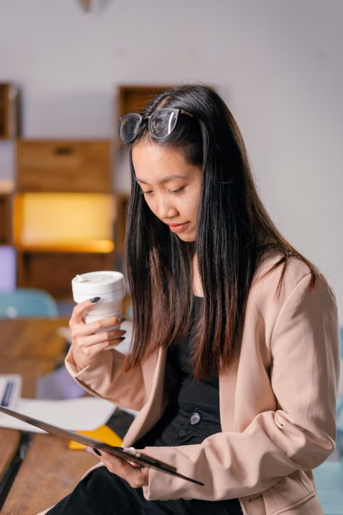 A woman holding a cup while reviewing a document.