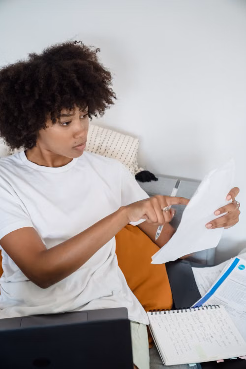 An independent professional reviewing documents beside her laptop