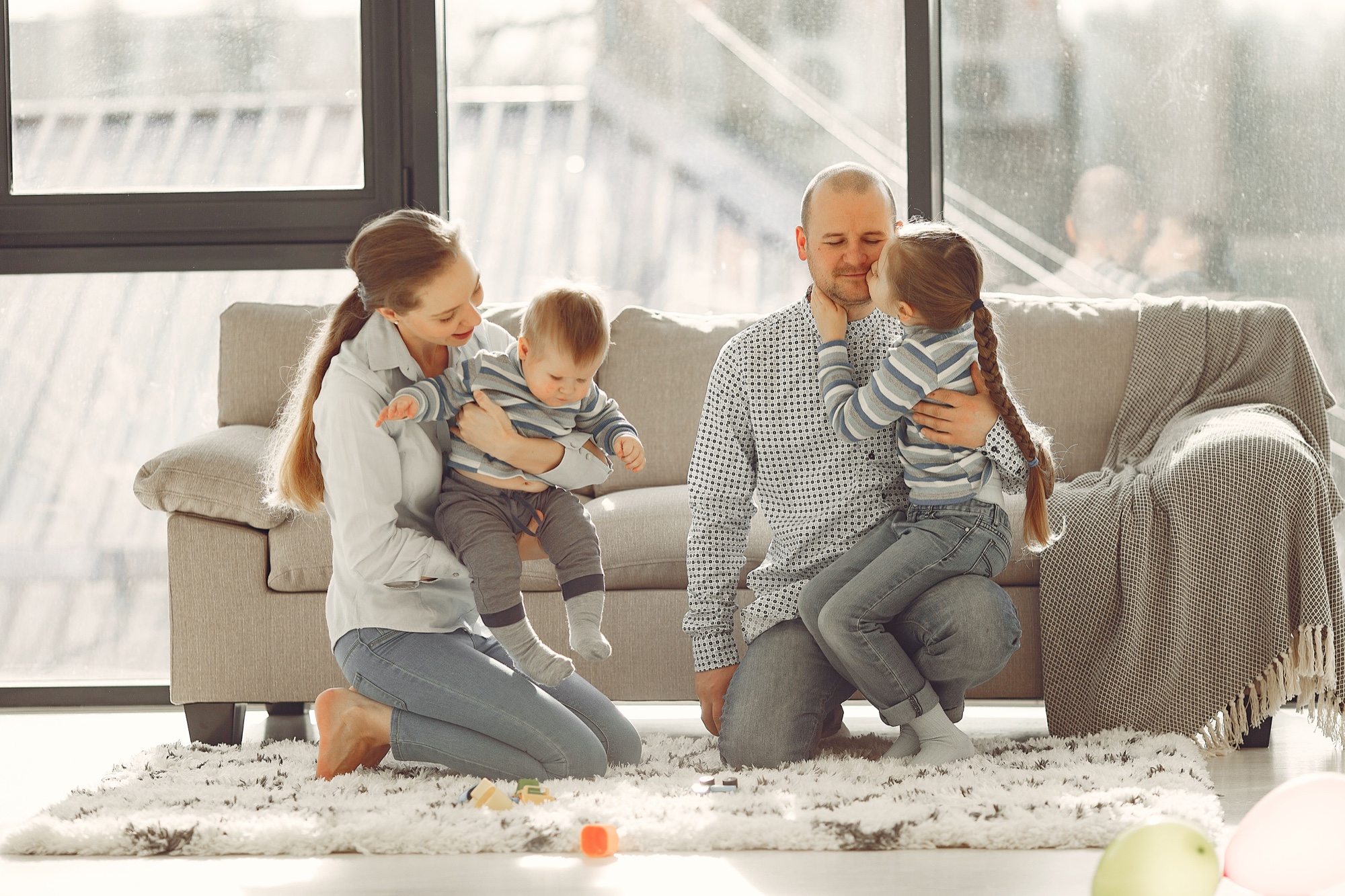 Parents playing with their two children in a sunlit living room