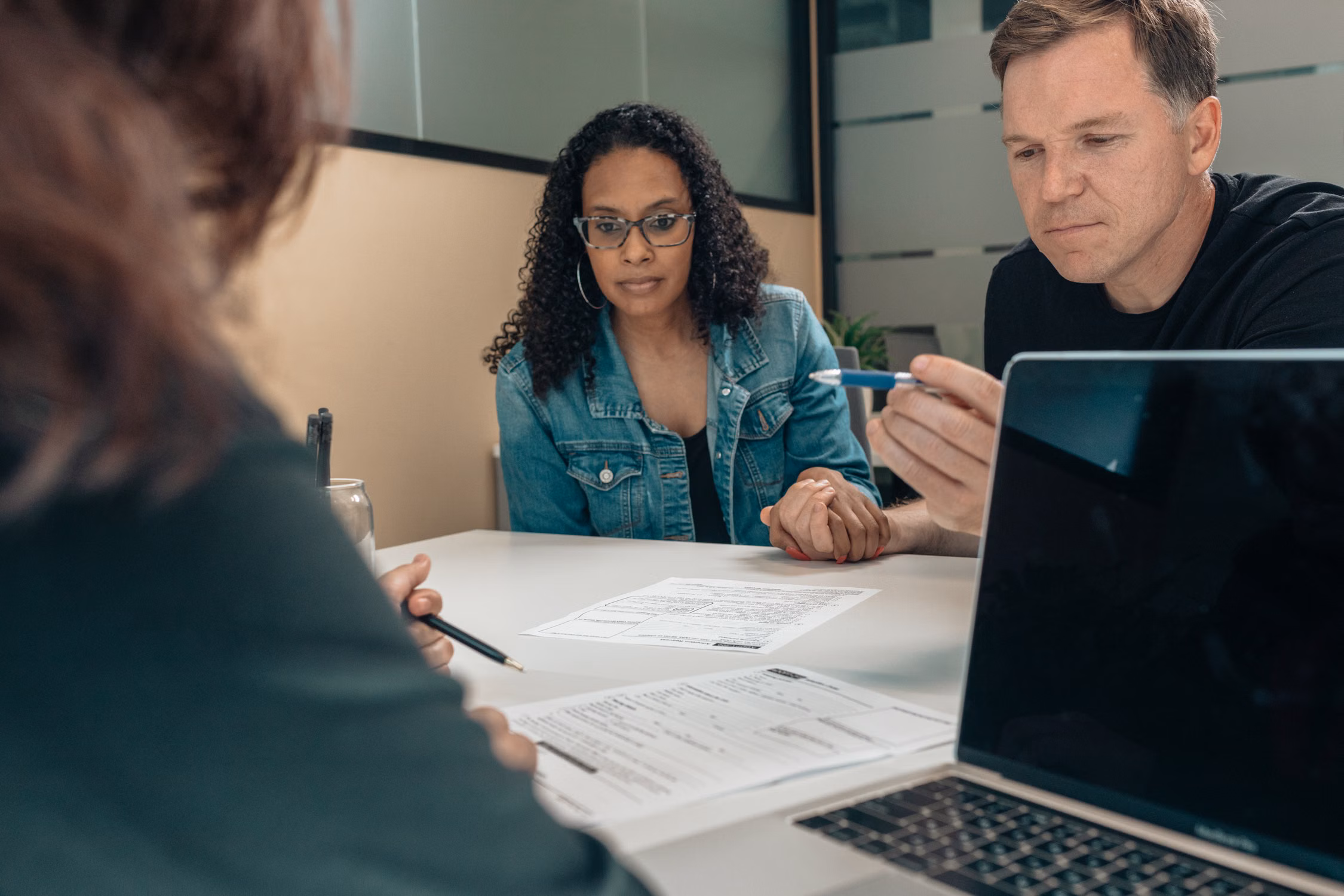 Three adults discussing paperwork around a table.